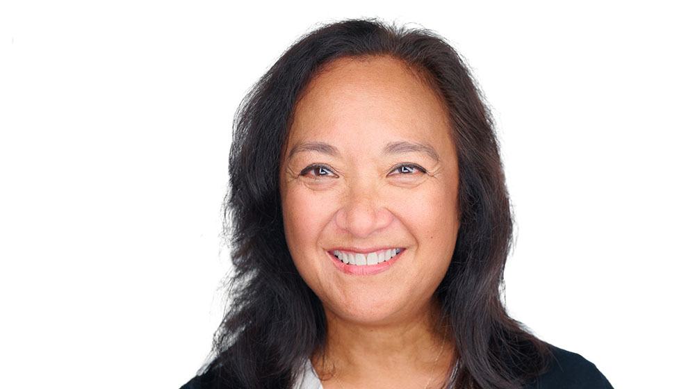 Headshot of Jorgia Connor, wearing white shirt and black jacket, smiling